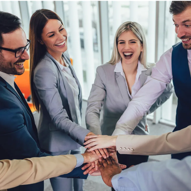 A team of colleagues joining hands together in an office
